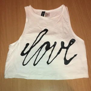 Magtröja/ topp - Vit magtröja/topp med svart text, köpt på H&M för längesen men inte använt den, den är i bra skick. Jag säljer den för 80-90kr. Det är storlek XS men skulle säga att en person med XXS skulle kunna ha den med för den är liten i storleken. Köparen står för frakten. 