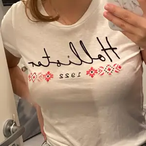 En vit hollister t-shirt med tryck på bröstet, använd några gånger och är i storlek XS. Ner stoppad på både bild ett och två. 
