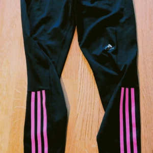 Adidas tights - Sköna tunna träningstights från Adidas, svarta med rosa/lila ränder på halva benet, använda några gånger och är i gott skick 🙂 snörning invändigt och även en liten innerficka, storlek 38. Finns i Västerås 🌸🌸🌸