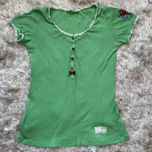 Grön ribbad Odd Molly t-shirt  - En grön ribbad Odd Molly topp i bra skick. Vit spets vid armarna och urringningen. Passformen är hyfsat medel, dock är den ganska stor i storleken. Originalpris var 380kr. 