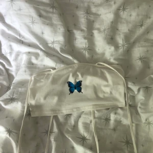 Gullig tröja med fjäriltryck - Säljer en vit croppad tröja från shein med fjärilstryck på! Tröjan är ganska genomskinlig, men supersöt och väldigt bekväm. Man kan justera axelbanden utifrån hur tajt man vill ha tröjan. Priset är exklusive frakt. 