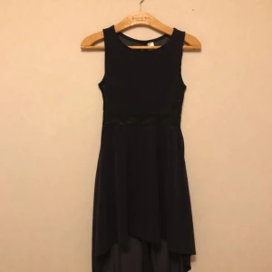  - Mörkblå klänning från H&M. Underkjol med luftigt tyg över. Lite längre bak. Spetsdetaljer på sidorna. Storlek XS. Frakt tillkommer.