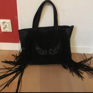  - Rymlig väska i fejkläder, en gång lagad dragkedja och några av ”diamanterna” på framsidan har trillat av (se bild tre). Annars i mycket gott skick. 