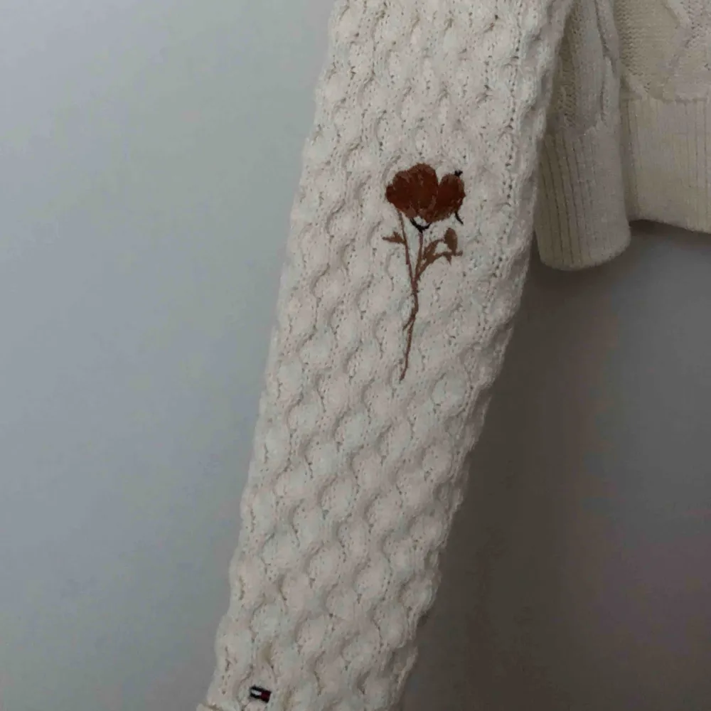 Säljer denna fina stickade tröja med hög krage från Tommy Hilfiger. Detaljer med broderade blommor i olika färger finns på framsidan samt ärmar. Använd ca tre gånger. . Stickat.