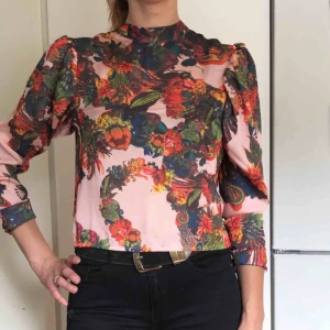  - Mönstrad blus med puffärm och knäppning i ryggen.