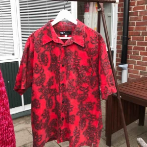  - En röd skjorta med blommigt mönster på! 