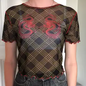 Mesh top från Urban outfitters. Nyskick! Fint drakmotiv i fram och är rutig med röda sömmar. Tröjan är i storlek L men jag på bilden har oftast xs-s, passar dock större. Betalning sker via swish och jag kan både frakta mötas upp köpare står för frakt;)