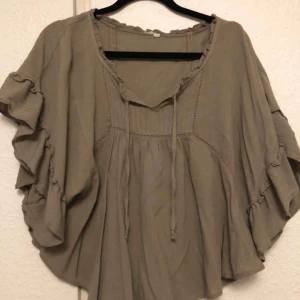  - En skönt blus i en gråaktig färg. Blusen är väldigt luftig och behaglig att bära. I fram finns snöre om man vill knyta det vid bröstkorgen. Man kan välja att ha knutet eller låta snörena hänga. Köpare står för frakt. 