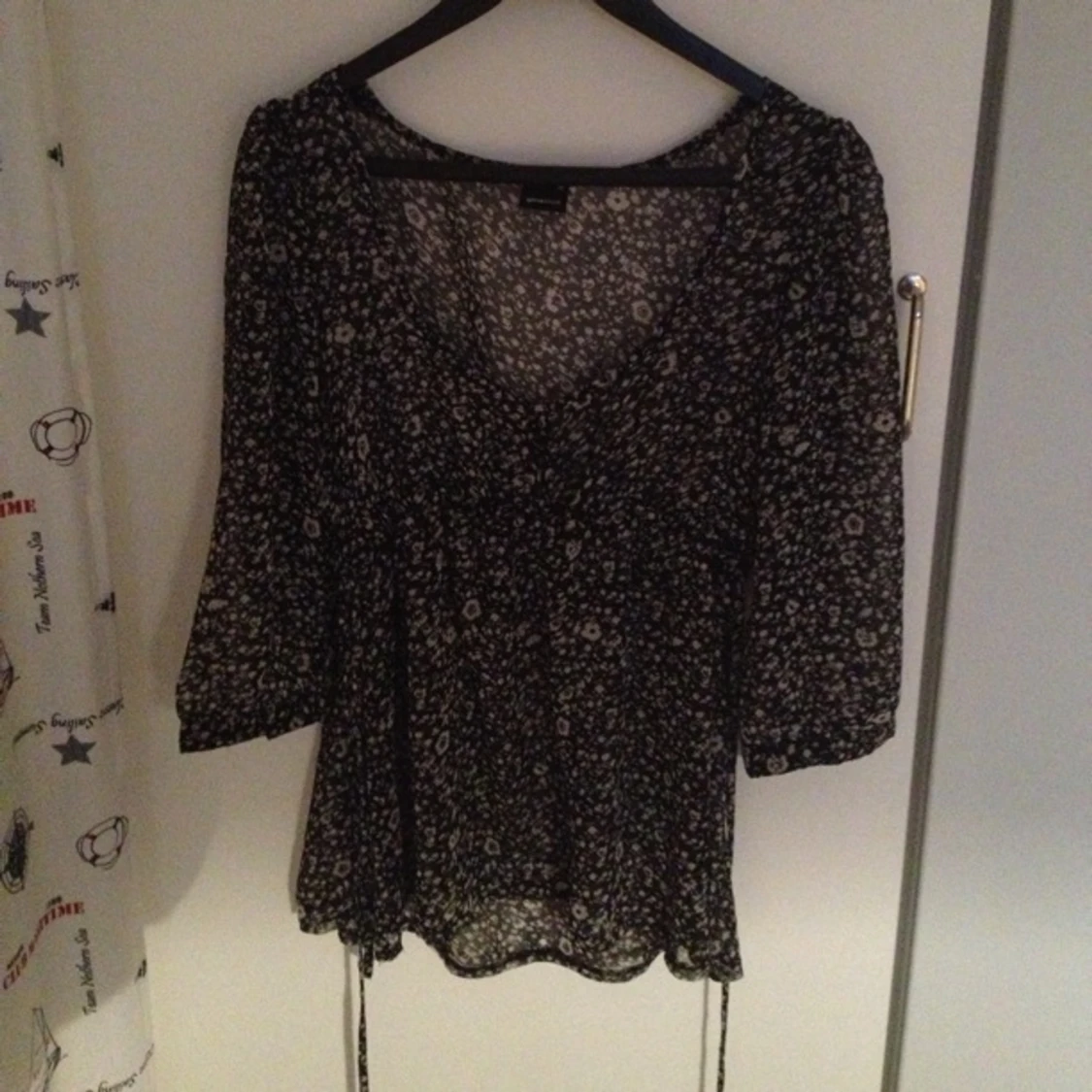 Långärmad sval blus svart/vit-mönstrad med snörning i midjan, svarta knappar.