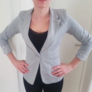  - En grå kavaj med lite blommor på ärmar. Helt ny!