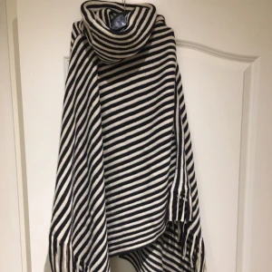  - En poncho från Lindex. Ränder i vitt och marinblå. Köparen står för frakten.