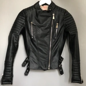 Skinnjacka från chiquelle storlek 38 - Skinnjacka från chiquelle i storlek 38. Modellen heter Moto jacket black och är köpt för 699 kronor. Jackan köptes för runt 5 månader sedan och är lite pösig vid armarna. Men annars er den i bra skick :) Alla dragkedjorna funkar bra. Skriv privat för fler bilder eller om du är intresserad av att köpa :) 