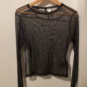 Glittrig festtopp - Svart, genomskinlig, väldigt glittrig festtopp från HM som är snygg att ha under nått plagg eller bara som det är. Aldrig använd, så tröjan är i väldigt bra skick. 