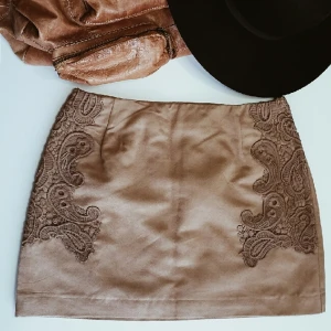  - Super snygg kjol från H&M i moka-imitation med vakert detalj. Helt oanvänd med prislappen kvar, säljer på grund av fel storlek. 