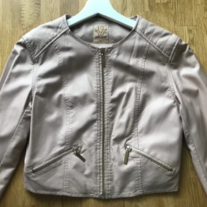  - Skinnjacka i ljusrosa färg.