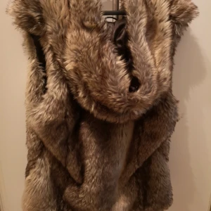  - Pälsväst i storlek xl (oäkta päls) från nelly, väldigt sparsamt använt ca 2-3 gånger, fickor i fram och en stor mysig luva. Håller värme jättebra passar till höst vår och vinter. Kan skickas mot porto. 