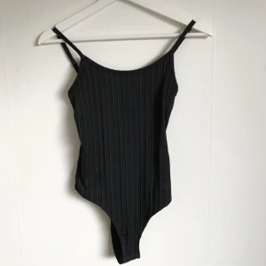  - Svart randig body. Använd endast en gång. Säljes då den inte kommer till användning. Stretchigt material.