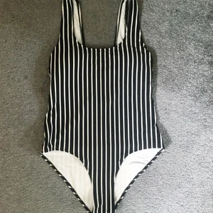 Baddräkt  - Svart och vitrandig baddräkt. Den är i storlek 36 och kuporna är vadderade. Djup rygg. Endast använd en gång eftersom den är lite för liten på mig. Skriv till mig om du är intresserad eller om du har några frågor. Fraktkostnad tillkommer!🌻
