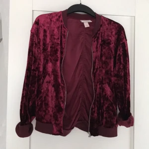  - Bomberjacka/kofta i vinröd sammet XS från Monki (förra årets)  Silverfärgad dragkedja, mudd nedtill och vid ärmslut, fickor fram på vardera sida  Använd enstaka gång, väldigt fint skick! 