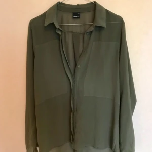  - Militärgrön, tunn blus från Gina. Bra till fest och vardags, hänger snyggt på kroppen.   Frakt ingår! 