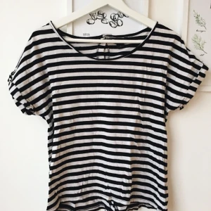  - Svart-vit randig t-shirt med knappar i ryggen från Monki. 100%bomull