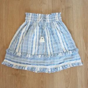 Supersöt sommarkjol - Jättefin kjol med volangkanter och snören med tofsar. Har ganska hög midja med resår, och tyget är vävt 🦋 frakt ingår i priset!