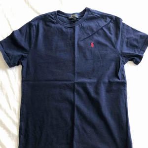  - Mörkblå t-shirt med rött polomärke