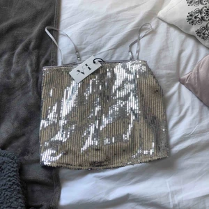  - Ett silvrigt linne i paljett från nakd x Linn Ahlborg, aldrig använd med lappen kvar, strl 36💍 Köparen står för frakt💕