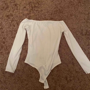 Body - Vit off-shoulder body från Nelly.com Använd fåtal gånger (i nyskick) Bild nr 2 är från deras hemsida Köparens tår för frakten, skriv pm för ytterligare frågor:)