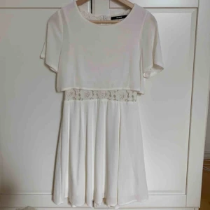  - En vit kortärmad klänningsliv knäna. Använts en gång. Spets i midjan som är see thru. Har en underkjol och är inte jätte fladdrig. Den tunna kortärmade blusen sitter fast i klänningen.