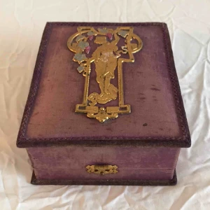  - Smyckeskrin i lila sammet med art noveau-dekoration. 20 x 15 cm. Lite nött på utsidan men går att stänga ordentligt! Fodrat på insidan.