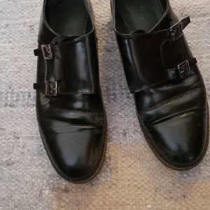 Svarta skori lack med spänne - Vår/höstskor med fina detaljer och fin passform. I lack, som jag upplever hållt sig snyggt trots att dom är välanvända. Några repor finns om man tittar på nära håll, använt men gott skick helt enkelt.  