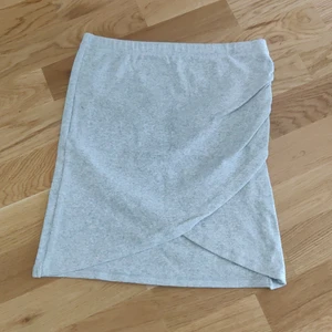 Ljusgrå mjuk kjol Bik bok stl S - En ljusgrå kjol i mjukt material från Bikbok i storlek S. Passformen är tajt med en liten omlott detalj. Fraktkostnaden tillkommer.