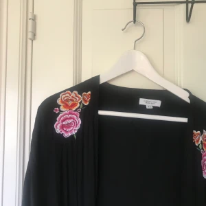 Svart kaftan med broderi - Säljer en svart kaftan med blommiga broderier i storlek M/L. Frakt tillkommer🌞