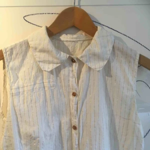  - FRI FRAKT! Vit topp med guldglittriga ränder. Fin till svarta höga kostymbyxor, till exempel.  Alltid mängdrabatt vid flerköp!