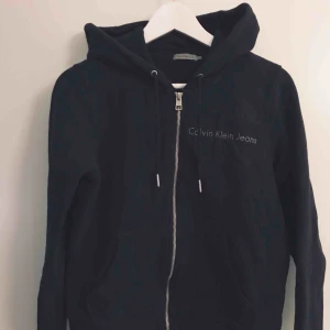  - Svart huvtröja i lite kortare modell, från Calvin Klein jeans. Använd men inga defekter. Skickar med postnord skicka lätt för 58kr.
