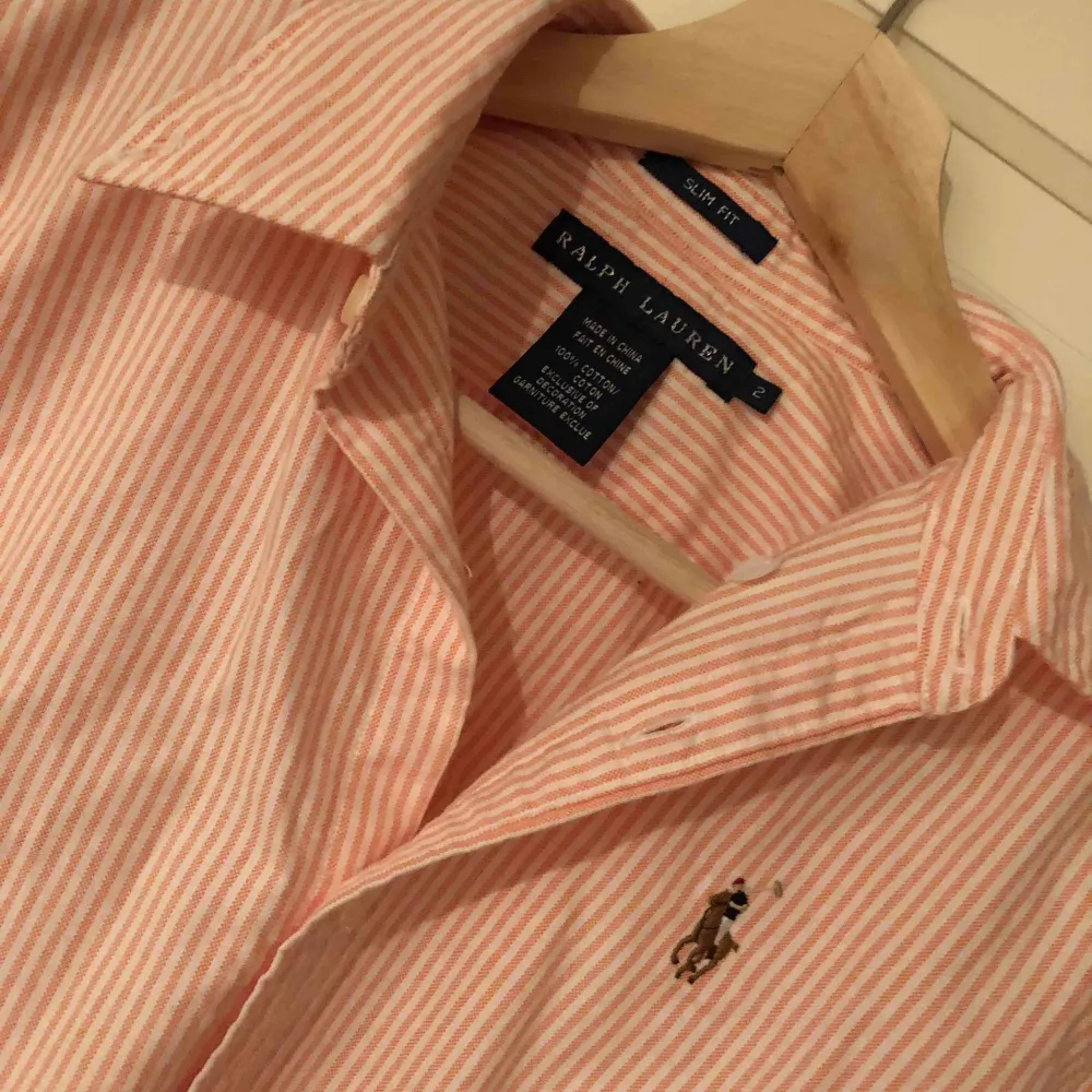 Aprikosfärgad skjorta från Ralph Lauren i USA i storlek 2 vilket motsvarar 34/XS. I fint skick, äkta. Modellen slimfit med ränder. Behöver strykas Hund finns i hemmet. Skjortor.