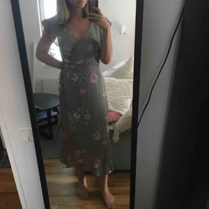 - Grön omlottklänning med blommigt mönster. Endast använd en gång så den är i jättefint skick! 