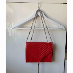  - Röd liten väska med silver detaljer. Silvrig kedja som man kan göra längre/kortare. Har ett innerfack med dragkedja. Frakt tillkommer!