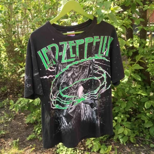  - Vintage T-shirt med dubbelsidigt tryck (samma fram/bak). Istället för coola detaljer visas två av skavankerna så du vet vad du köper. Lite sliten kring halsen på två ställen + några malhål. Övrigt gott beg skick. Mer L än XL