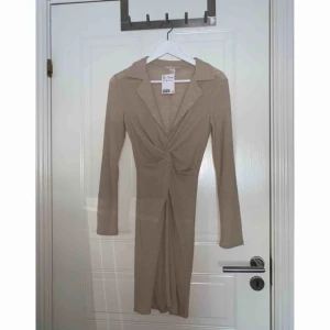  - Beige långärmad klänning från H&M Trend, med djup V-ringning. Aldrig använd med lappen kvar. Originalpris 349 kr. Frakt ingår!