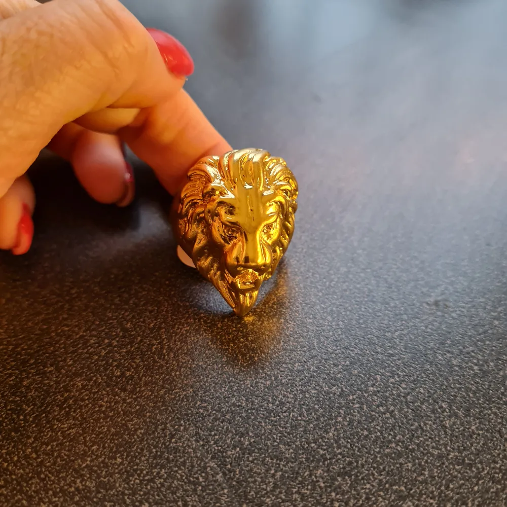 Guldfärgad ring i form av lejonhuvud i storlek 12, ca 22 mm i diameter. Oanvänd!. Accessoarer.