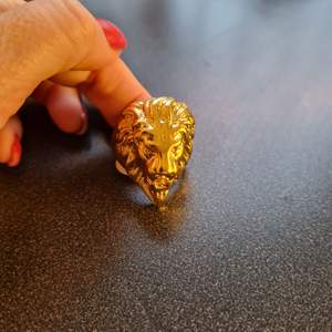 Guldfärgad ring i form av lejonhuvud i storlek 12, ca 22 mm i diameter. Oanvänd!
