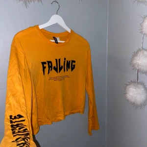 Långärmad tröja med tryck strl S - Orange långärmad tröja med tryck i fram och på höger ärm. Tunt tyg vilket gör att den kan bäras även på sommaren.