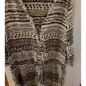 Snygg playsuit svart/vit - I silkigt svalt tyg.knäppbar Urringning. Snöre man kan dra åt i midjan. Svart/vit. Djur och rökfritt hem.Frakt tillkommer på 63:- spårbart. jag samfraktar gärna!