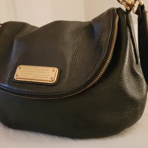 Väska - Super snygg stilren Marc by Marc Jacobs väska säljes pga används ej. Väskan köptes för 5000 :- på NK Väskan är bra skick. Finns ett bra fack där man får plats med mycket. Äkta läder. Det går att ta bort axelremmen om man vill det. Har ni fler frågor om väskan är det bara att skriva på meddelande. Mått: 25 x 9 x 17 cm