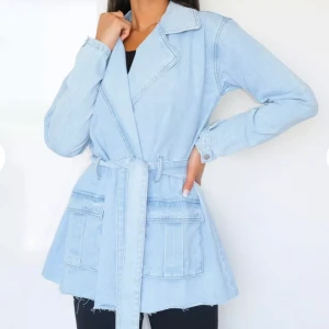 Missguided light blue self tie waist denim jacket - Ljusblå jeansjacka i en längre passform och skönt material.  Anpassar sig bra efter kroppen och justeringar går att göra med midjebandet. Helt nytt skick med prislappen på. Köpt för 450kr.  
