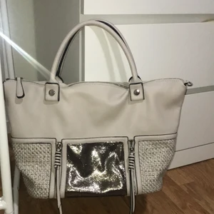 En beige handväska  - En beige handväska i bra skick med snygga detaljer framifrån! Perfekt för vardaglig användning som exempelvis jobb/skolväska. Skriv priv om ytterligare bilder önskas!  