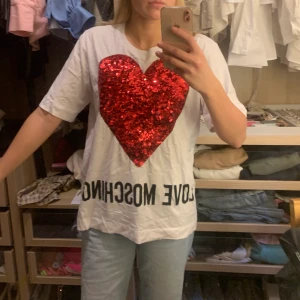 Moschino tshirt - En klassisk moschino T-shirt köpt i USA 2019, använd fåtal gånger säljer då den inte kommer till användning. Pris 500kr exklusive frakt. Är us Size 12 vilket motsvarar 42. 💓