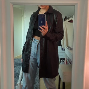 Läderkappa/skjorta - Jättesnygg och stilren svart läderkappa från NA-KD. Den går att använda både inomhus och utomhus då den är filtad/fodrad på insidan. Går att använda som kappa, skjorta och skjortklänning. Helt oanvänd. Säljer för 199 + frakt som köparen står för :) 